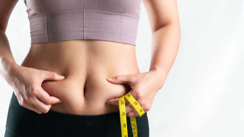 junge frau greift sich seitlich auf die bauchfalten bauch
